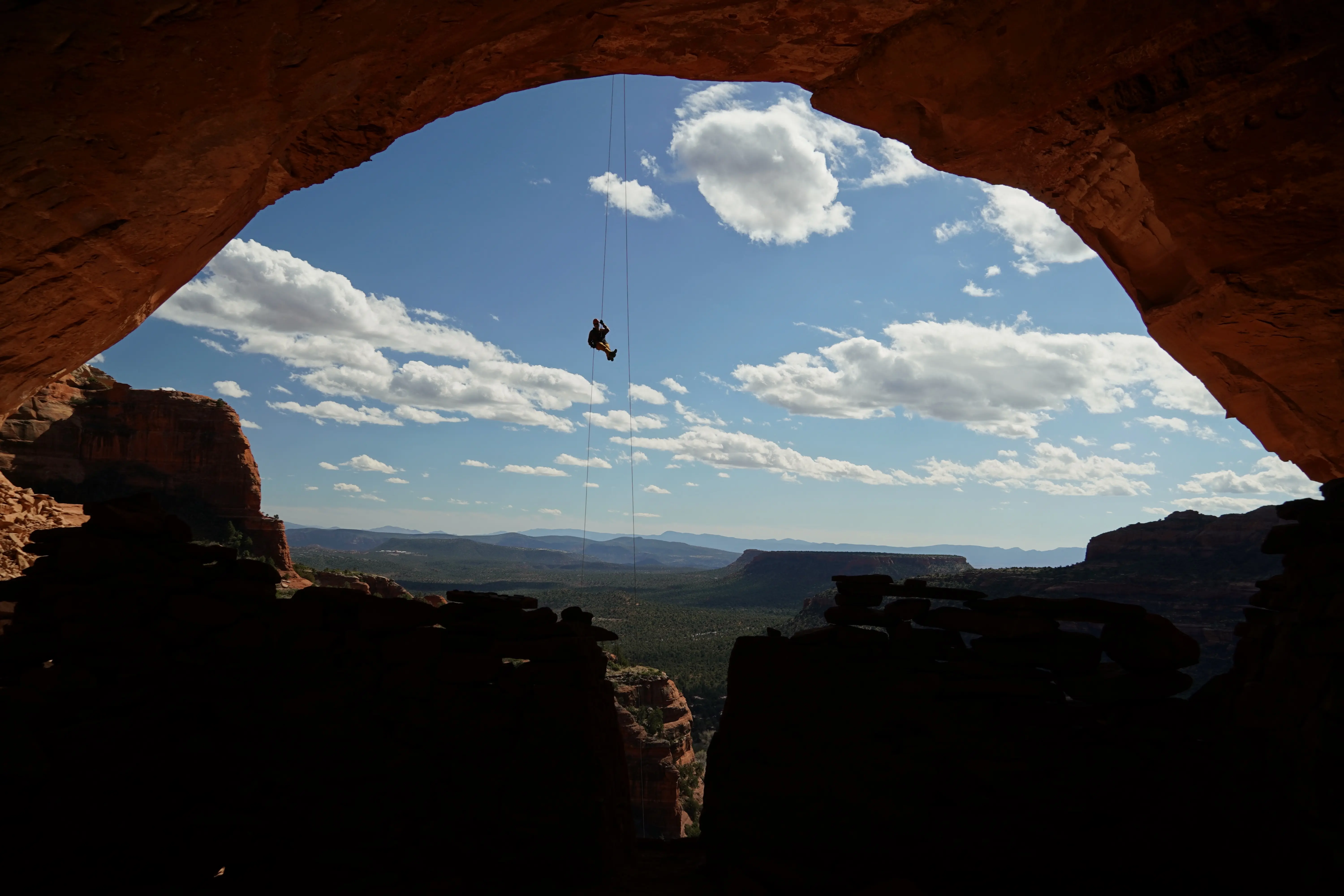 David Haynes checking out the Anasazi cliff dwellings while rappelling. Near Sedona, Arizona. Photographed by Shane Haynes